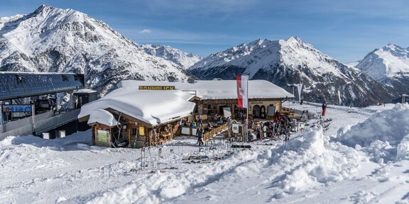 A cozy mountain cabin in the snow, surrounded by majestic mountains. The sky is clear and sunny, perfect for a winter day. - Sonnblick - Hochsölden
