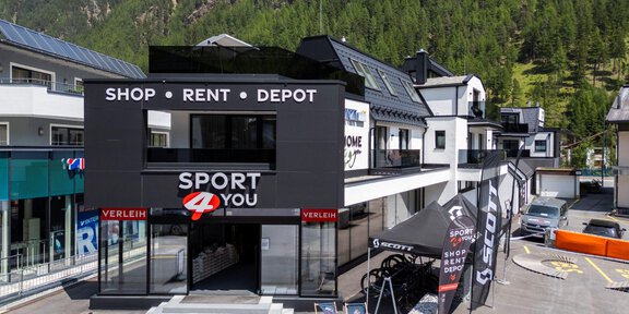 A modern sports store named "Sport 4 You." It offers services such as rental and storage and is surrounded by mountains. - Sport4You Filiale Giggijoch - Sölden