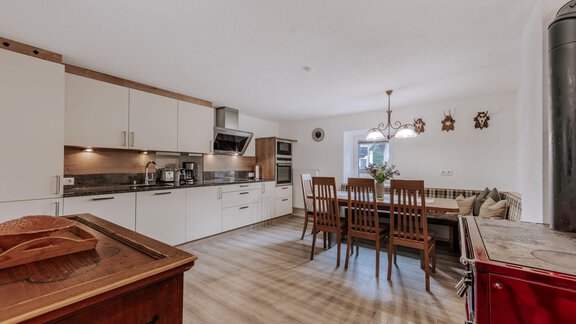 A modern kitchen with bright cabinets and a wooden dining table set. The room is well-lit and offers a cozy atmosphere. - Landhaus Waldesruh - Haiming