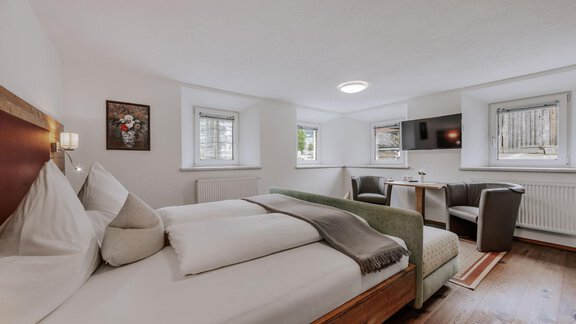 A modern room with a double bed and a cozy seating area. Large windows provide plenty of daylight and a pleasant atmosphere. - Landhaus Waldesruh - Haiming