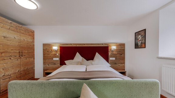 A modern bedroom with a large double bed and wooden wardrobes. The walls are light and the lighting creates a cozy atmosphere. - Landhaus Waldesruh - Haiming