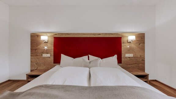 A cozy bedroom with a double bed and rustic wood design. The walls are painted in soft colors and modern lamps provide pleasant light. - Landhaus Waldesruh - Haiming