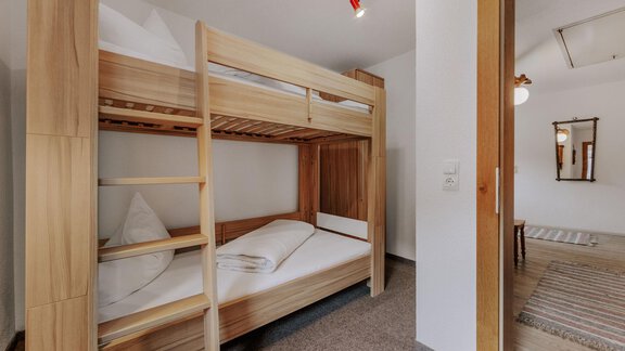 A cozy room with a wooden bunk bed. The walls are bright, and the space feels inviting and tidy. - Landhaus Waldesruh - Haiming