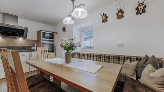 A cozy dining area with a wooden table and a bench. On the table, there is a vase with flowers, and the walls are adorned with decorative trophies. - Landhaus Waldesruh - Haiming