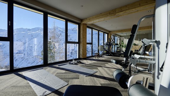 A modern gym with large windows and a view of snow-covered mountains. The equipment and mats are ready for training. - Alpenhotel Laurin - Hochgurgl