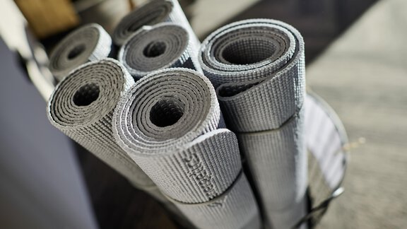 A basket with rolled yoga mats in gray. The mats are neatly stacked and ready for use. - Alpenhotel Laurin - Hochgurgl