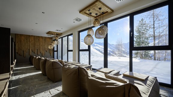 A modern relaxation room with comfortable bean bags and large windows. Outside, you can see snow-covered mountains and trees in the background. - Alpenhotel Laurin - Hochgurgl
