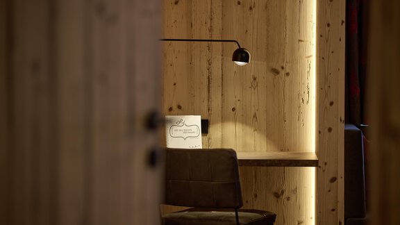 A cozy office with wooden-paneled walls. A modern chair and a desk lamp create a pleasant atmosphere. - Alpenhotel Laurin - Hochgurgl