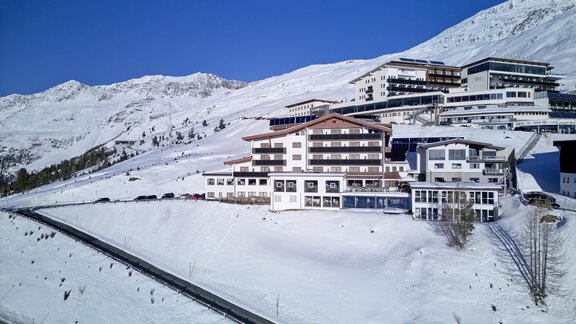 A modern hotel in a snowy mountainous landscape. The surrounding mountains are clearly framed by the blue sky. - Alpenhotel Laurin - Hochgurgl
