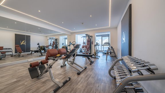 A modern gym with various workout equipment and large windows. The space is bright and inviting, perfect for sports and fitness. - Hotel Angerer Alm - Hochgurgl