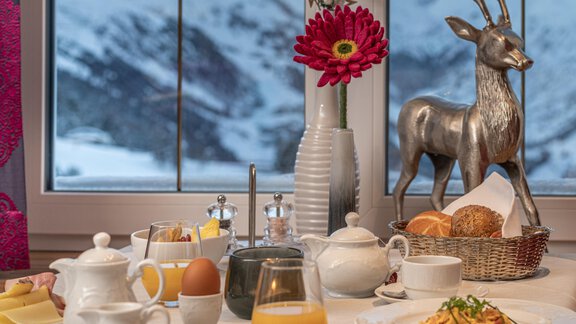 A beautifully set breakfast table with various foods and drinks. In the background, snow-covered mountains can be seen. - Hotel Angerer Alm - Hochgurgl