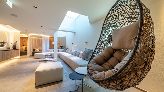 A modern living room with a cozy hanging swing and a bright, inviting atmosphere. The furnishings are stylish and minimalist. - Hotel Angerer Alm - Hochgurgl