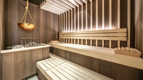 A modern sauna with wooden elements and soft lighting. The benches provide space for relaxation and well-being. - Hotel Angerer Alm - Hochgurgl