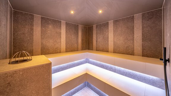 A modern steam bath with elegant gray walls and indirect lighting. The room is clean and inviting, perfect for relaxation. - Hotel Angerer Alm - Hochgurgl