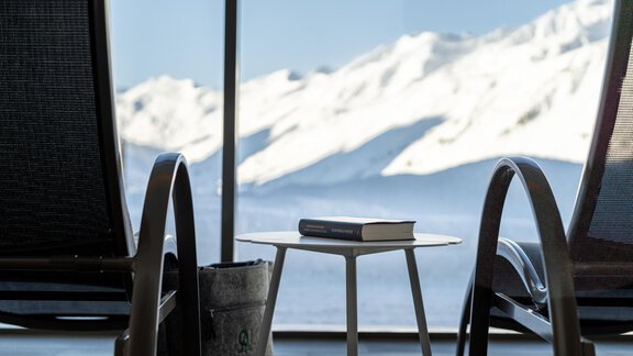 A cozy room with two loungers and a small table. In the background, snow-covered mountains can be seen. - Hotel Angerer Alm - Hochgurgl