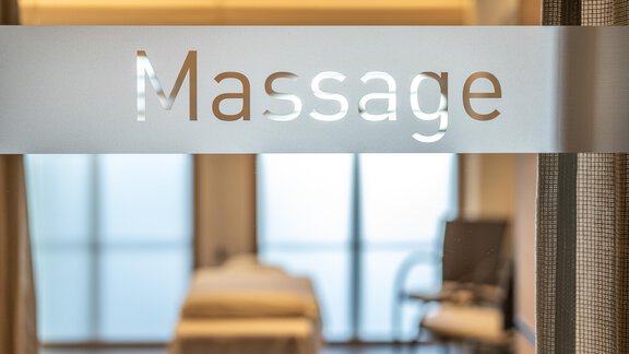 A soothing massage room with a view of large windows. The labeled glass door displays the word "Massage." - Hotel Angerer Alm - Hochgurgl