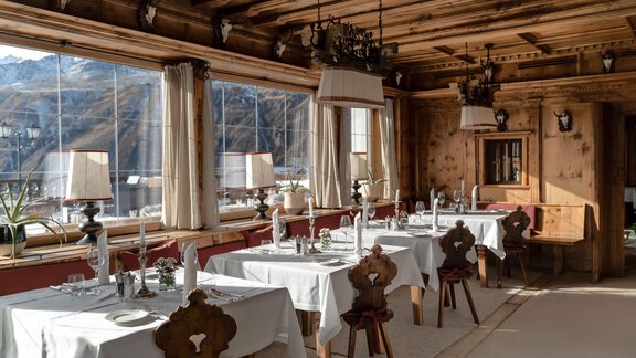 Ein elegantes Restaurant mit Holzwänden und großen Fenstern. Die Tische sind schön gedeckt und bieten einen Blick auf die Berge. - TOP Hotel Hochgurgl - Hochgurgl