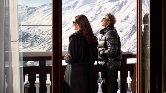 Zwei Personen stehen auf einem Balkon und blicken auf schneebedeckte Berge. Die Sonne scheint und die Aussicht ist beeindruckend. - TOP Hotel Hochgurgl - Hochgurgl