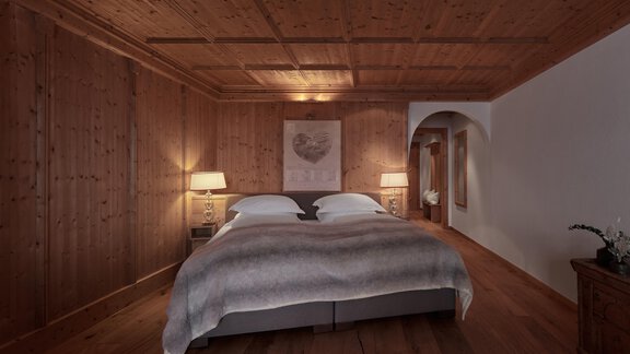 Ein gemütliches Schlafzimmer mit Holzverkleidung und einem großen Bett. Die warmen Lichter schaffen eine einladende Atmosphäre. - TOP Hotel Hochgurgl - Hochgurgl