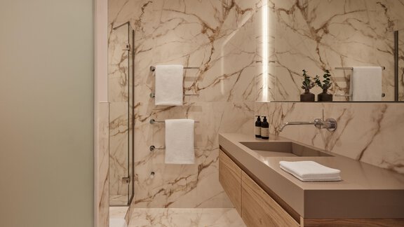 Ein modernes Badezimmer mit marmorierten Wänden und eleganten Holzdetails. Es gibt eine Dusche, Handtücher und dekorative Pflanzen auf der Ablage. - TOP Hotel Hochgurgl - Hochgurgl