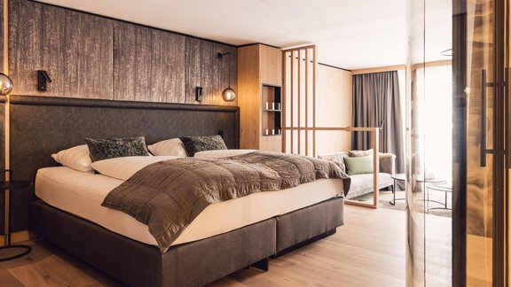 A modern bedroom with a large bed and elegant furniture. The room is bright and inviting, with large windows and cozy details. - 4 * Superior Hotel Schöne Aussicht - Hochsölden