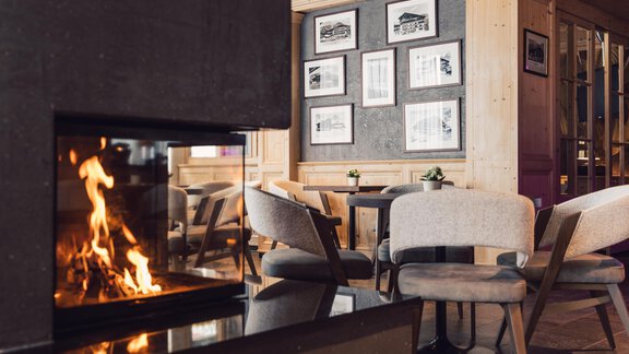 A modern café with a fireplace and comfortable armchairs. Pictures hang on the wall, and the room feels inviting and cozy. - 4 * Superior Hotel Schöne Aussicht - Hochsölden