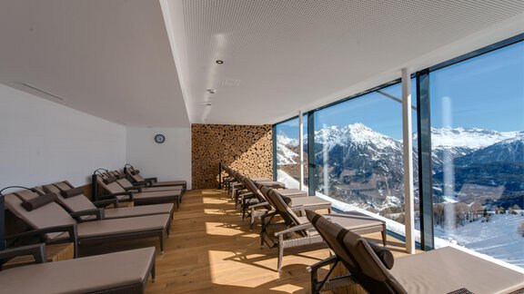 A relaxing room with loungers and large windows offering a view of the mountains. The wooden floor and modern furnishings create a cozy atmosphere. - 4 * Superior Hotel Schöne Aussicht - Hochsölden