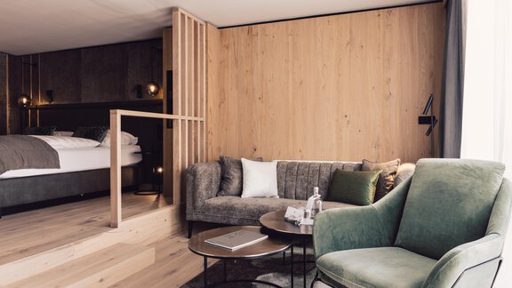 A modern hotel room with a cozy living area. The walls are made of wood, and there is a small table with chairs. - 4 * Superior Hotel Schöne Aussicht - Hochsölden
