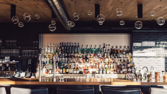 A stylish bar with a large selection of spirits and modern light bulbs. The space has an elegant atmosphere with wooden and metal accents. - 4 * Superior Hotel Schöne Aussicht - Hochsölden