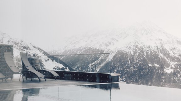 A modern pool with a view of snow-capped mountains. Peaceful desks and loungers invite relaxation. - 4 * Superior Hotel Schöne Aussicht - Hochsölden