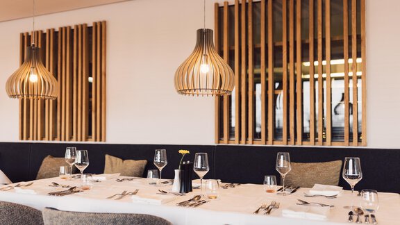 A modern restaurant with elegant wooden elements and stylish lamps. The table is set for a festive dinner. - 4 * Superior Hotel Schöne Aussicht - Hochsölden