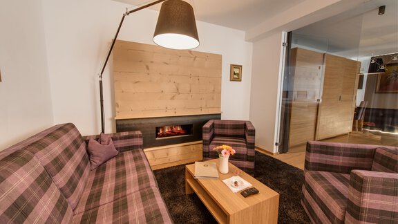 A cozy living room with checkered sofas and a wood stove. The room is modern and inviting with a warm light. - 4 * Superior Hotel Schöne Aussicht - Hochsölden