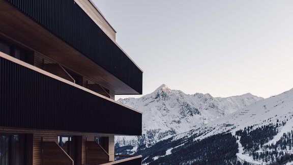 A modern building with a balcony and a view of snow-covered mountains. The landscape conveys a calm winter atmosphere. - 4 * Superior Hotel Schöne Aussicht - Hochsölden