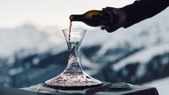 An elegant wine glass is filled with red wine, while the snow-covered mountains are visible in the background. The atmosphere feels calm and luxurious. - 4 * Superior Hotel Schöne Aussicht - Hochsölden