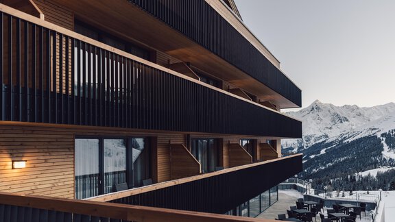 A modern building in the mountains with wooden cladding and large windows. The surroundings showcase an impressive mountain landscape. - 4 * Superior Hotel Schöne Aussicht - Hochsölden