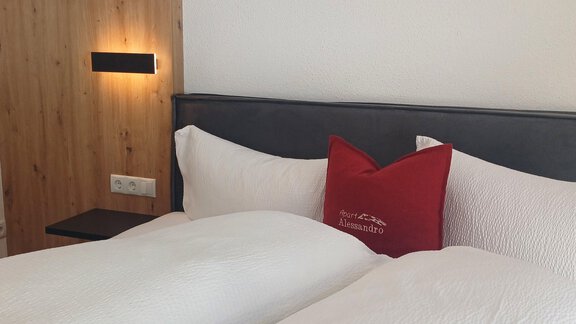A cozy bedroom with two single beds and white bedspreads. On the wall, there is a wooden shelf with a modern lamp. - Apart Alessandro - Huben