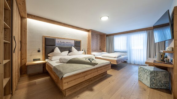 A modern, cozy hotel room with two beds and wooden interior. Large windows provide plenty of daylight. - Genusshotel Alpenblick - Huben