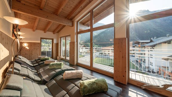 A relaxing chill-out room with comfortable loungers and large windows. The sun shines in and provides a view of the mountains and the surroundings. - Genusshotel Alpenblick - Huben