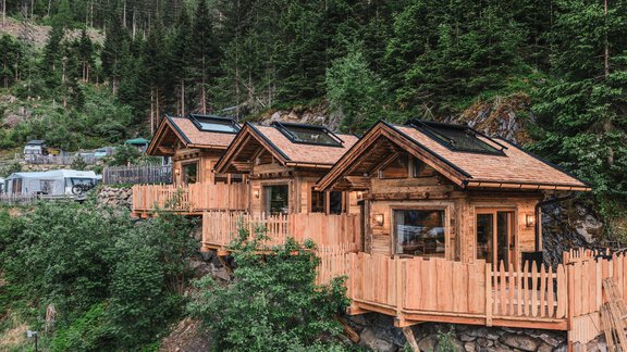 Drei gemütliche Holzhütten umgeben von Bäumen und Felsen. Sie stehen auf einer erhöhten Terrasse mit einem schönen Blick auf die Natur. - Naturcamping Kuprian - Ötztal - Huben