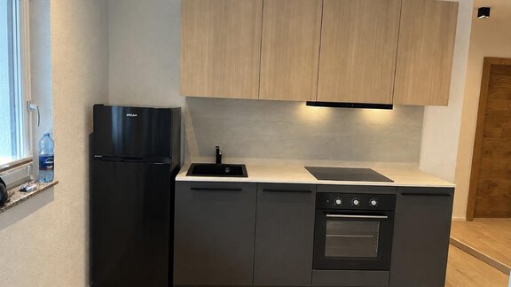 Eine moderne Küche mit schwarzen Geräten und Holzregalen. Der Raum ist hell und gut gestaltet. - ONO Apartments - Huben