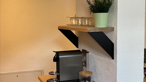 Ein gemütlicher Bereich mit einem Holzregal und einer Kaffeemaschine. Es gibt eine kleine Pflanze auf einem Regalbrett an der Wand. - ONO Apartments - Huben
