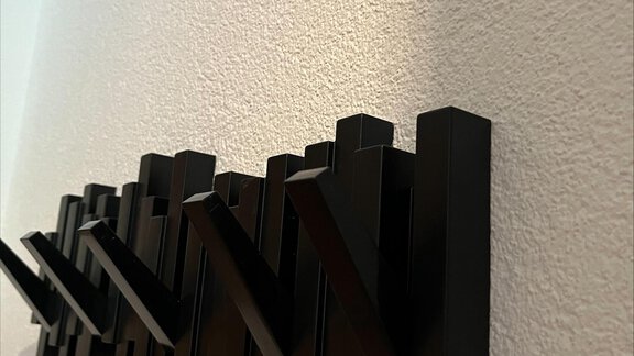 Eine moderne Garderobe aus schwarzem Metall mit geometrischen Formen. Sie ist an einer hellen Wand montiert und sieht elegant aus. - ONO Apartments - Huben