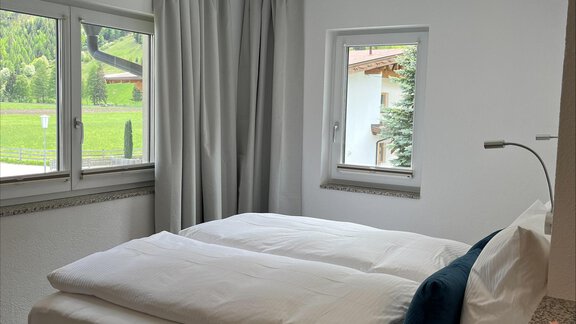 Ein helles Schlafzimmer mit zwei Betten und großen Fenstern. Der Raum ist modern eingerichtet und bietet einen Blick ins Grüne. - ONO Apartments - Huben