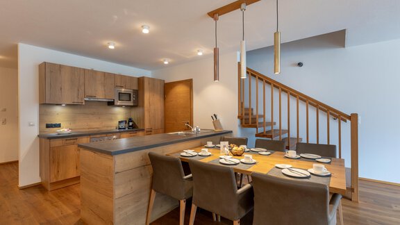 Moderne Küche mit Holzregalen und eleganter Eleganz. Ein Esstisch ist für mehrere Personen gedeckt. - Alpenappartement Central Valley Penthouse - Längenfeld