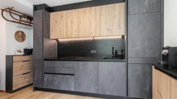 Eine moderne Küche mit schwarzen und holzfarbenen Schränken. Der Raum ist hell und minimalistisch gestaltet. - Apartment DoLa - Längenfeld