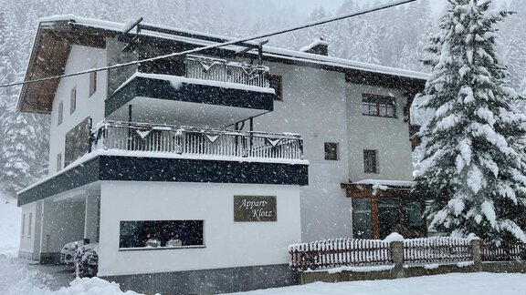 Ein charmantes Gebäude im Schnee mit mehreren Balkonen. Die Umgebung ist winterlich und verträumt, umgeben von Tannenbäumen. - Appart Klotz Alpenglück - Längenfeld