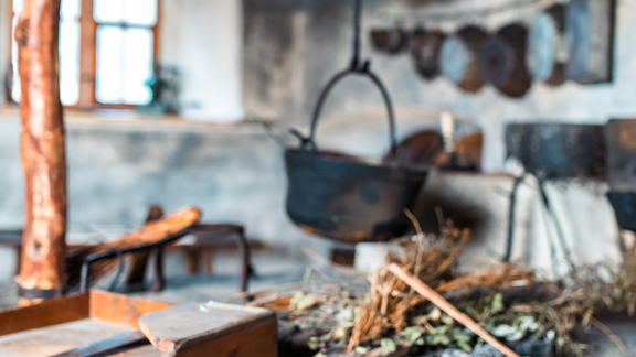 A traditional kitchen with rustic utensils and a large cauldron. Wooden boards and fresh bread are on the table. - Bauernhaus Auer - Längenfeld