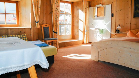 A cozy room with wood paneling and plenty of natural light. A table, a chair, and a couch invite relaxation. - Ferienhaus Auer - Längenfeld