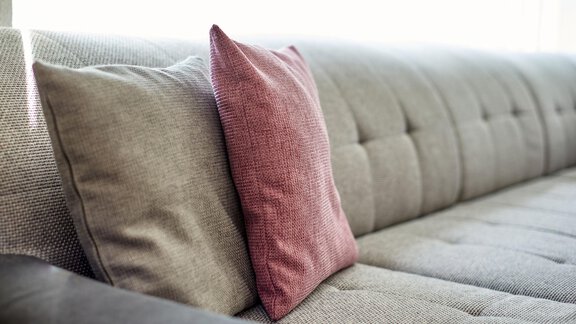 Ein modernes Sofa mit zwei Kissen. Eines ist grau und das andere ist rosa. - Ferienhaus Schrankogelblick - Längenfeld