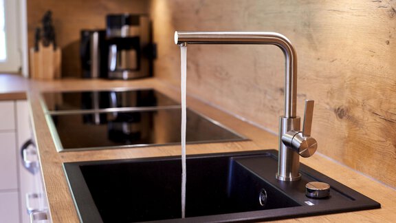 Eine moderne Küche mit einem eleganten Wasserhahn und einer schwarzen Spüle. Im Hintergrund sind Kochplatten und Küchenutensilien sichtbar. - Ferienhaus Schrankogelblick - Längenfeld